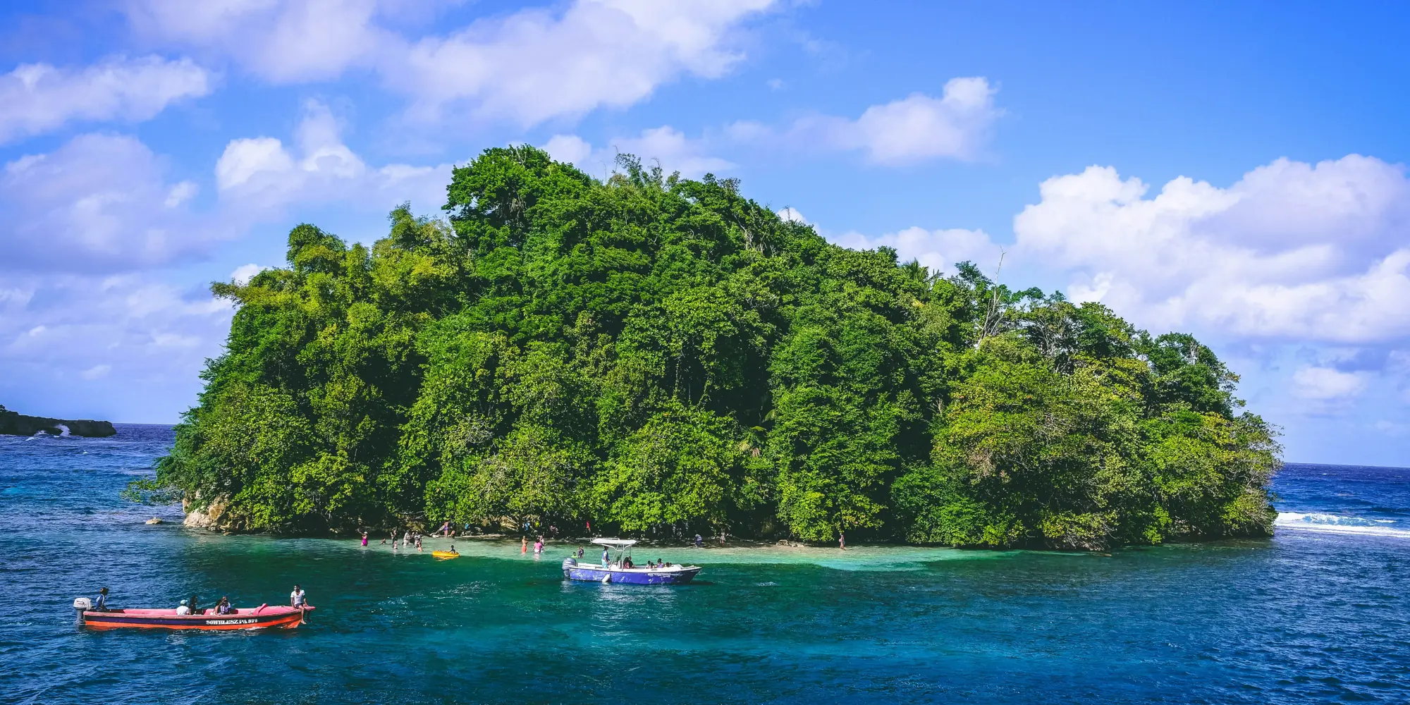Kleine grüne insel mit booten im meer vor jamaika tauchen mit haien